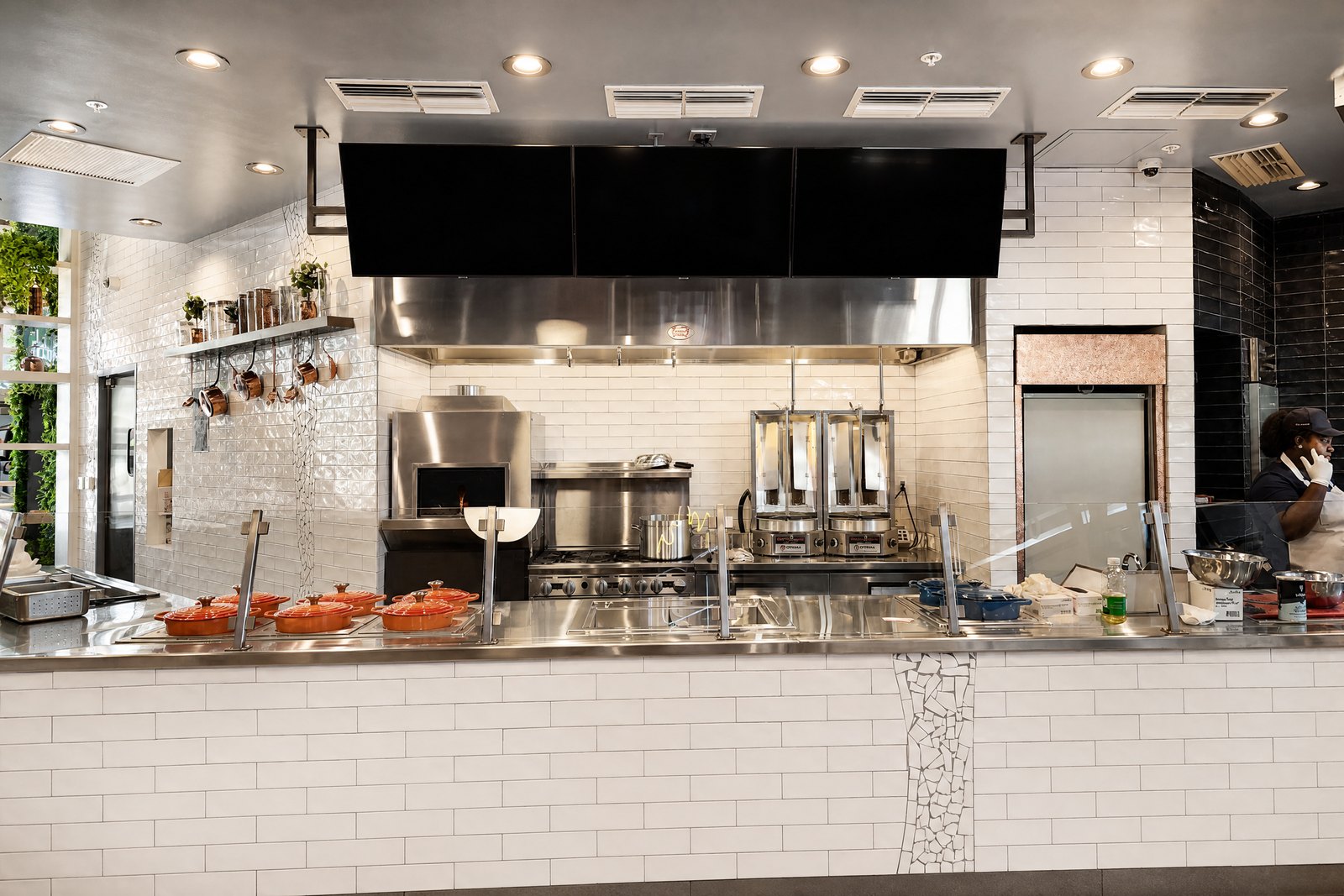 Mazza Kitchen service line with white tile, stainless equipment and display screens