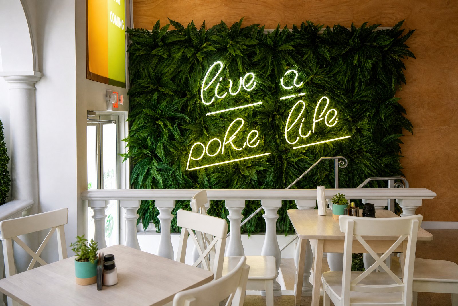Poke Life dining area with foliage wall and illuminated Live a Poke Life sign