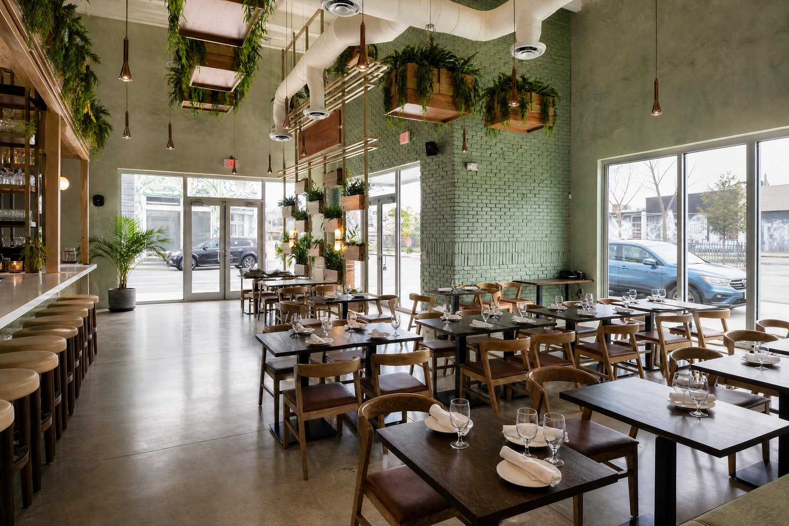 Sette Osteria dining room with green brick wall, hanging planters and tables